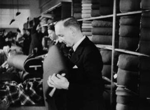 Szene aus den "Werbespots Dresdner Textil- und Modegeschäfte": Verkäufer bei Wilhelm Thierbach, Kleiderstoffe