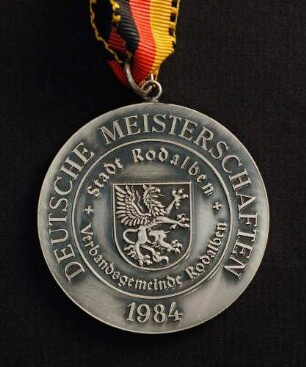 Silbermedaille Deutsche Meisterschaften in Kurzschrift und Maschinenschreiben in Rodalben 1984 am schwarz-rot-goldenen Band : Sammlung Deutscher Stenografenbund. Silbermedaille Deutsche Meisterschaften in Kurzschrift und Maschinenschreiben in Rodalben 1984 am schwarz-rot-goldenen Band. Messing, versilbert; Durchmesser 50 mm, Gewicht 49,5 g (1984; Deschler & Sohn, München). Dresden: SLUB R c 0537