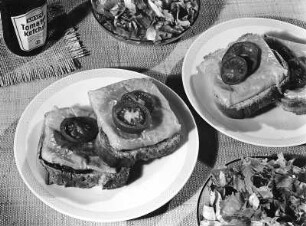 Krafts Rezeptaufnahmen. Käsetoasts mit Tomatenscheiben Daneben eine Flasche Kraft's Tomatenketchup und Salatschüsseln