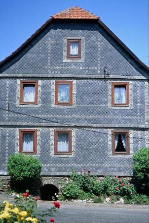 giebelständiges Schieferhaus, Kellereingang am Giebel, Bepflanzung am Sockel