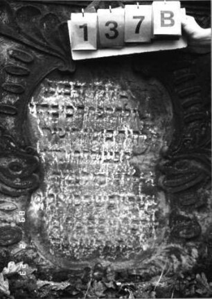 Grabstein 137 (Index: 99751946) Material: Sandstein Zustand: verwittert mit großem Textverlust Maße HxBxT: 164x98x14 cm Beschreibung: ädikulaart. St. m. Viertelsäulen, in Voluten auslaufender Rundbogenaufsatz Symbolik: drei Kronen, Eichenlaub, Ranken: Grabstein 137B