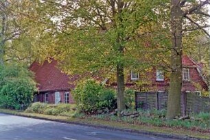 Möllner Landstraße (5): traufständiges Bauernhaus aus Backstein: Straßenfront mit Eingangstür: Giebelseite Wohntrakt: Hecke, Straßenbäume, Sichtschutzwand