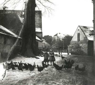 Frohburg. Bauernhof. Hofansicht mit zwei Mädchen, Hühner fütternd