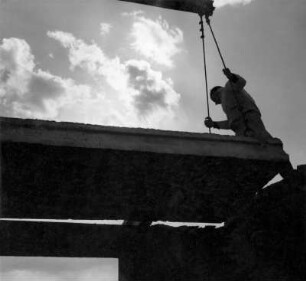 Dresden. Bauarbeiter positioniert Deckengroßblock beim Absetzen per Kran