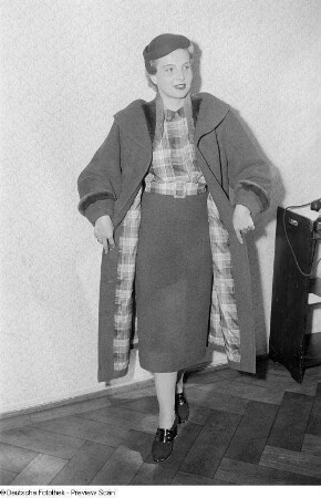 Eine Frau posiert mit Mantel und Hut bei der "Internationalen Messemodenschau", Herbstmesse 1953
