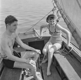 Elisabeth Gremmler übernimmt das Ruder des Segelboots, neben ihr sitzt ein Mann in Badehose