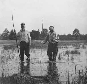Familienbilder : Rudolf Zimmermann gemeinsam mit einem anderen Mann mit Stecken in der Hand durch einen Teich watend, Pfingsten 1932