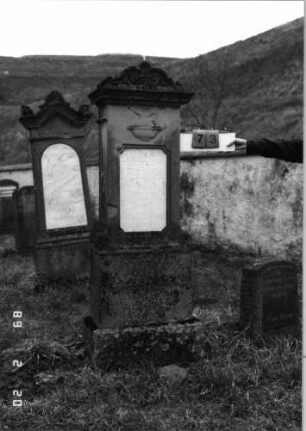 Grabstein 73 (Index: 99798573) Material: Sandstein, Schriftplatte Marmor Zustand: gut Maße HxBxT: 187x47x24 cm Beschreibung: Stele mit Volutenaufsatz, Schriftplatte, Sockel Symbolik: Kanne in Schale: Grabstein 73
