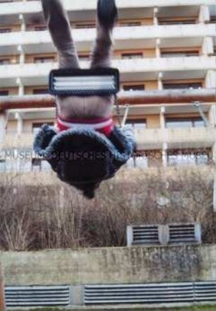 Schaukelndes Kind aus der Untersicht fotografiert, im Hintergrund Wohnhaus (Altersgruppe 14-17)