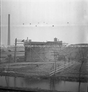 Brückenbau und Schornstein an einem Fluss