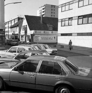 Brunnenstraße: vorne parkende Pkw, dahinter Gebäude, im Hintergund das Hochhaus "Liebe", Blick Richtung Süden