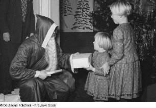 Weihnachtsmann beim Überreichen von Geschenken an Kinder auf der Weihnachtsfeier des VEB Kartographie