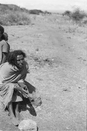 Eine Person der Arsi-Oromo : Eine Person der Arsi-Oromo sitzt auf einem Stein am Wegesrand