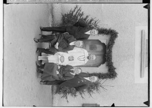 Primizfeier Ruf-Eisele in Sigmaringendorf 1936; Neupriester mit Verwandten und Primizbräutchen vor geschmücktem Hauseingang