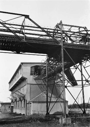 Kopfstation einer Transportanlage für Schüttgüter. Auf der Stahlfachwerkbrücke Umlenkrollen für Seilzüge, am Gebäude (Zwischenbunker?) Rutschen zur Beladung von Straßenfahrzeugen