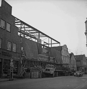 Firma Carl Hoffmann: Hindenburgstraße: Elektrohandel: Neubau: Aufbau des Stahlgerüsts: davor Bauzaun und Lkws: links Wohn- und Geschäftshaus des Haushaltswarengeschäfts Otto Möller: rechts Pkw: dahinter Wohn- und Geschäftshäuser