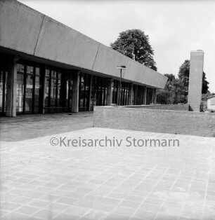 Stormarnhalle Bad Oldesloe: Am Bürgerpark: Blick von Nordosten: vorn Terrasse mit kleiner Mauer und Lampe: hinten rechts Lüftungsturm, Hütte und Bäume: 20. Juni 1968