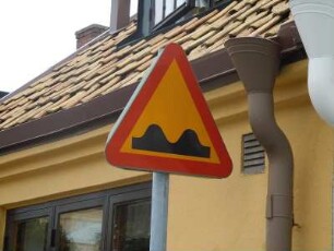 Ystad - Hinweisschild : Hinweisschild auf Bodenwellen vor einem niedrigen Haus in der Altstadt, aufgenommen in Ystad am 25. Juli 2010