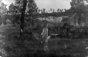 [Eisenbahnbrücke über einen Bach mit Knüppeldamm und einem Soldaten, der sich unter der Brücke befindet] (Postkarte von K. - F. Grossmann, 7/R 119, 26. Reserve-Division XIV Reserve-Kompanie, an den Gefreiten der Reserve Felix Grossmann, 3/R56, 121. Division)