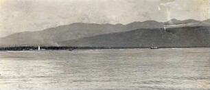 Bei Kingston, Jamaika. Blick von einem Kreuzfahrtschiff der Hapag auf Karibisches Meer mit Dampfer vor Küstenstreifen mit Leuchtturm gegen Bergwelt