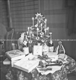 Kleiner geschmückter Weihnachtsbaum und Geschenke auf einem Tisch