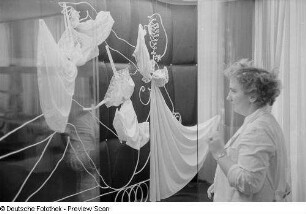 Eine Frau beim Dekorieren einer Vitrine der Leipziger Herbstmesse 1954 mit Damennachtwäsche
