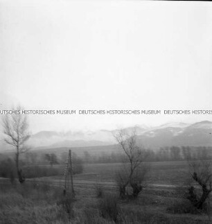 Aus einem fahrenden Zug fotografierte Landschaft mit verschneiten Bergen