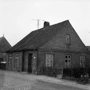 Bundesstraße B 75: altes Chausseewärterhaus: vorn rechts Zaun und Sträucher: links dahinter Zaun und Scheune