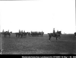 Geländeübung des Feld-Artillerie-Regiments Nr. 46 Enthält: Platte 7, Soldaten zu Pferd und auf mit Pferden bespannten Geschützlafetten paradieren vor berittenen Offizieren vorbei