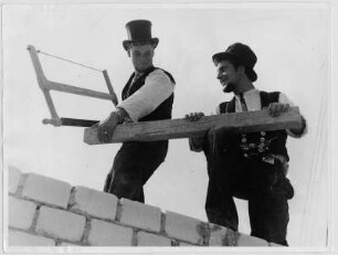 Wandernde Zimmerleute in Wanderkluft auf einer Baustelle