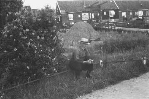 Dorfbild : Dorflandschaft mit Bewohner. Im Hintergrund ist eine Hebelbrücke, Holzhäuser und ein Heustapel