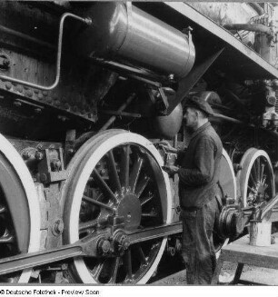 Fahrgestell einer Güterzuglokomotive der Baureihe 52. Arbeiter beim Streichen eines Radkranzes : Berlin-Tempelhof. Reichsbahnausbesserungswerk. Fahrgestell einer Güterzuglokomotive der Baureihe 52. Arbeiter beim Streichen eines Radkranzes