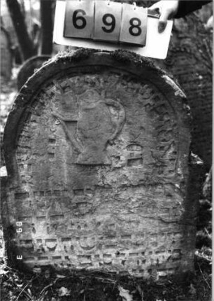 Grabstein 698 (Index: 99752366) Material: Sandstein Zustand: stark verwittert mit Textverlust Maße HxBxT: 84x69x9 cm Beschreibung: Stele, eingezogener Rundbogenabschluß, Schriftfeld eingetieft Symbolik: Levitenkanne: Grabstein 698