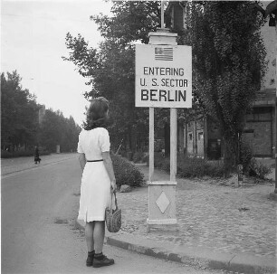 Berlin. Dame vor Hinweisschild "Entering U. S. Sector Berlin"
