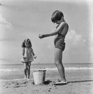 Zwei Kinder spielen mit Sand am Strand