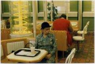 Alte Frau sitzt bei "Mc Donalds" (Altersgruppe 14-17)