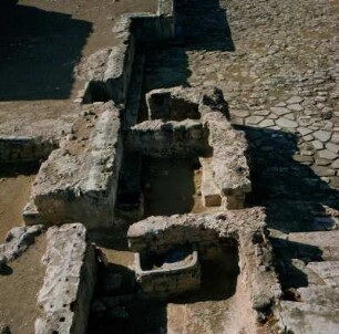 Phaistos. Älterer Palast. Links Absetzungssockel des Ältern Palastes. Davor Räume eines älteren Heiligtums. Rechts Westhof