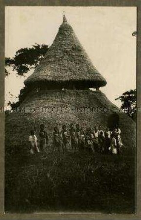 Gruppe afrikanischer Kinder vor einer als Schule genutzten Hütte