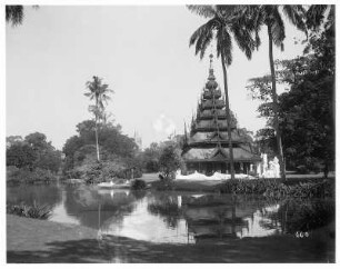 Rangun, schiefe Dagon Pagode : Rangun, Birma. Parklandschaft an einem Teich mit Touristen in Ruderboot, am Ufer Pagode mit großen Buddhastatuen