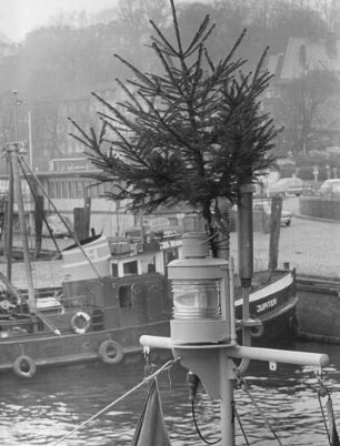 Weihnachten im Hamburger Hafen. Ein Weihnachtsbaum, befestigt an der Spitze des Mastes eines Schleppers.