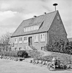 Amtsverwaltung: Amtshaus: Dorfstraße / Amtsweg: Außenansicht von Nordosten: davor Vorgarten mit Sträuchern und Büschen: vorn rechts Karre mit Milchkannen