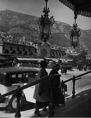 Monte Carlo. Vor dem Spielcasino. Zwei Frauen steigen aus einem PKW und steigen die Treppen zum Casino empor. Im Hintergrund ein Geschäftshaus