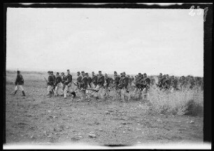 Gefecht bei Zoco el Tenain (=Zoco el Tenin (?)) und bei Beni Buiahi (?), am Fuße des "Monte Liata" (Provinz Nador, Marokko): Infanteristen ("Unterstützungstrupp") [des spanischen 8. Kavallerie-Regiments "Lusitania"] in hellgestreiften Uniformhosen, dunklen Uniformjacken und niedrige, runden Feldmützen mit Marschgepäck und Gewehren auf weiter Steppe (Seitansicht)
