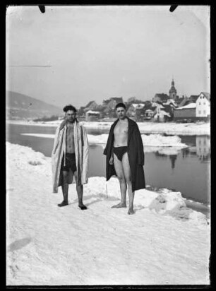 Schwimmer in Badehose und Bademantel am schneebedeckten Mainufer