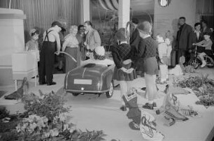 Mehrere Personen betrachten auf der Leipziger Herbstmesse 1955 ausgestellte Kindermode