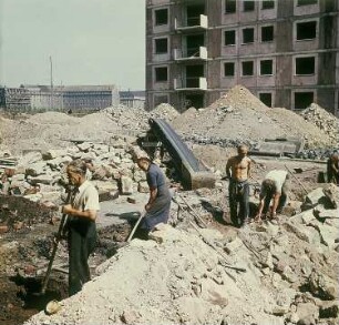 Dresden. Aufbauhelfer bei Tiefbauarbeiten vor einem Großblock-Rohbau