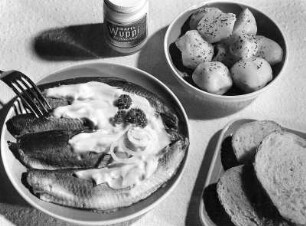 Krafts Rezeptaufnahmen. Teller mit Heringsfilets und Mayonnaisesoße, Glas mit "Kraft's Wuppi" Schale mit Pellkartoffeln und Teller mit Brot