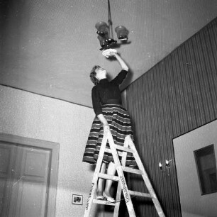 Hausfrauen leben gefährlich. Gefahr des Stürzens von der Leiter beim Putzen einer Deckenlampe