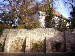 Ansicht von Südwesten mit Kirche in erhöht gelegenem Kirchhof über Kirchhofmauer mit Strebepfeilern (Wehrgang mit Steinbrüstung abgetragen)