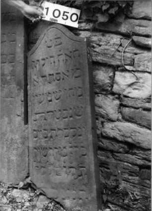 Grabstein 1050 (Index: 99630553) Material: Sandstein Zustand: unten abgeblättert mit Textverlust Maße HxBxT: 108x42x7 cm Beschreibung: Stele mit Konvexbogenabschluß: Grabstein 1050